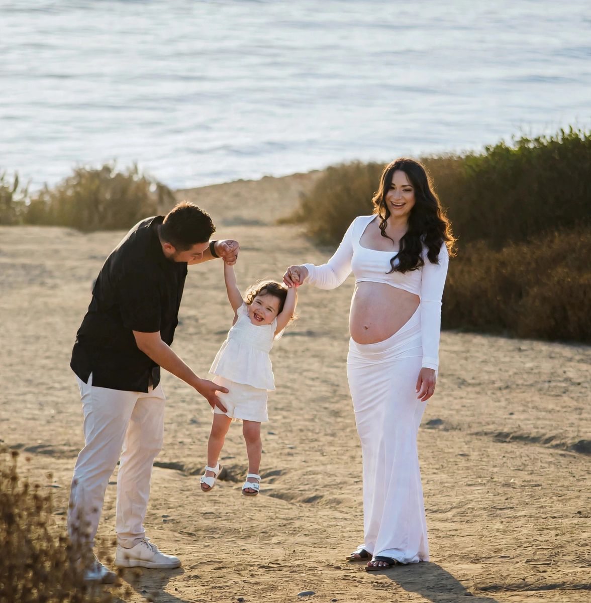 Araceli and her husband swinging their little girl at Sunset Cliffs
