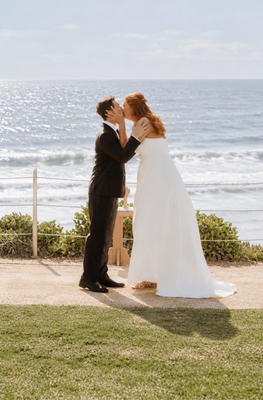 Emma and Cameron kissing at their ceremony above the ocean at Powerhouse Park